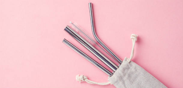 Reusable straws in cloth bag with pink background.