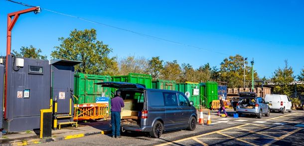 Vans and cars being unloaded at a recycling centre.