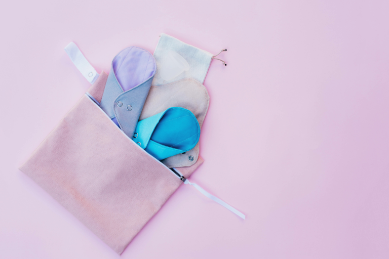 Wash bag filled with reusable pads on pink background.