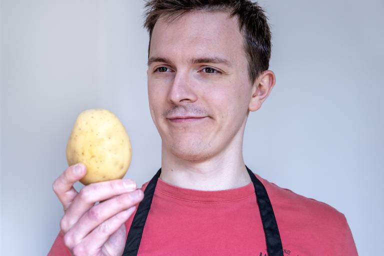 Man looking at a potato with a confused look.