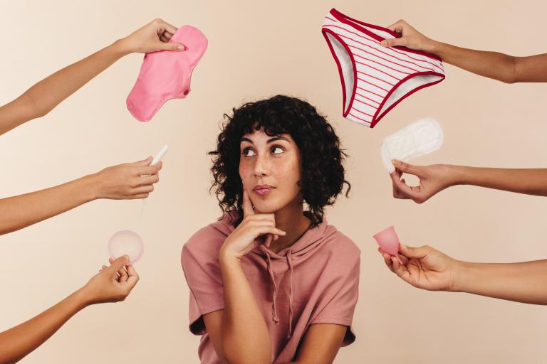 Person surrounded by various period products.