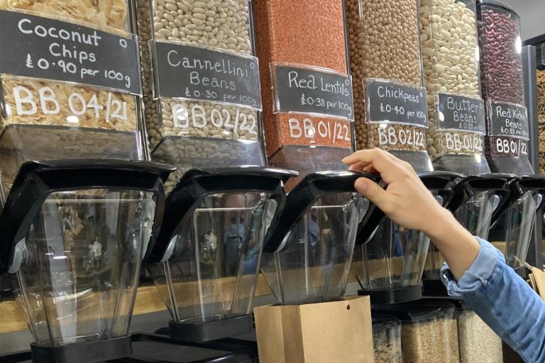 Hands filling a bag from refill shop dispensers.
