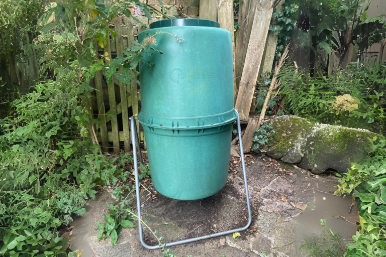 Tumbler compost bin in garden.