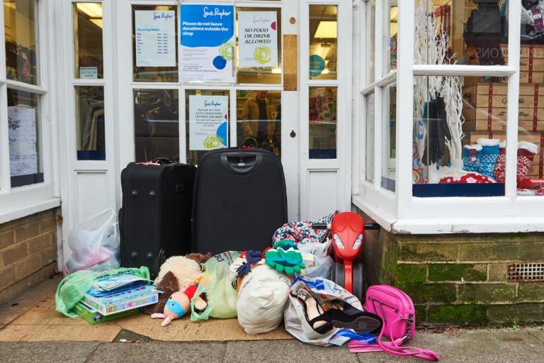 Bags of donations outside a charity shop doorway.