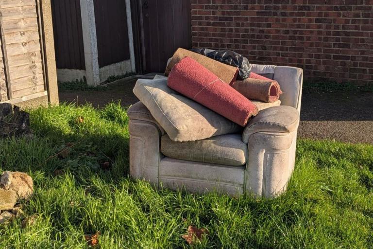 Armchair and rolled carpet on grassy land.