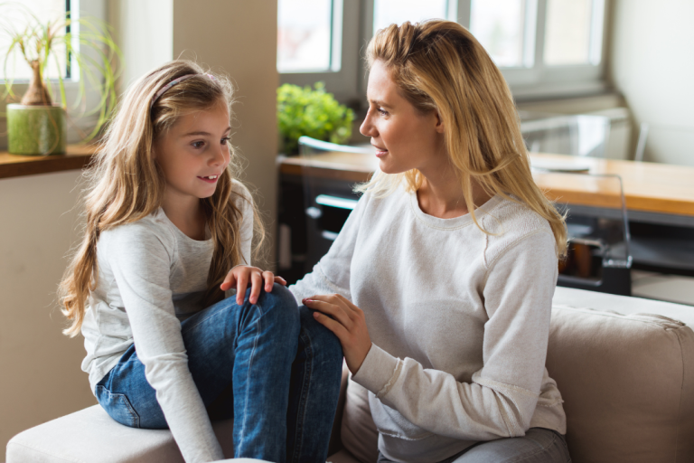 A child and parent sitting on a sofa talking